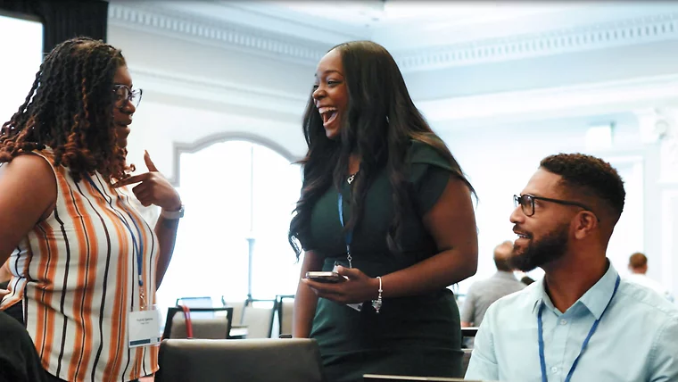 Three colleagues smiling and talking in an office.